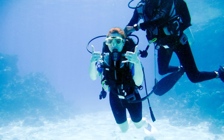 A beautiful girl diver shows hands gesture signal all well with