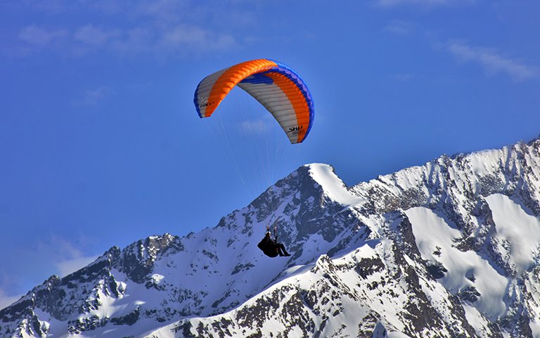 low-angle-view-person-paragliding-against-snowcapped-mountain