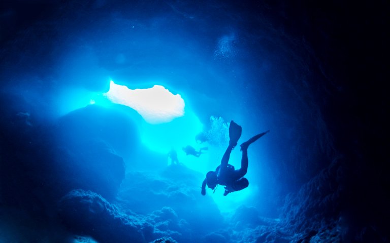 low-angle-view-scuba-divers-swimming-cave